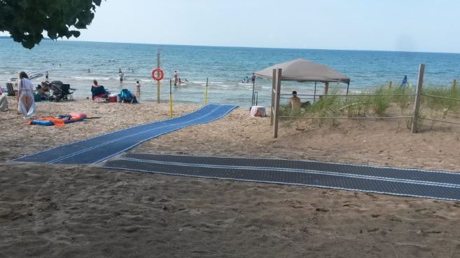 A beach and shoreline with two accesibility Mobi Mats connected to make a pathway for wheelchair access down to the water