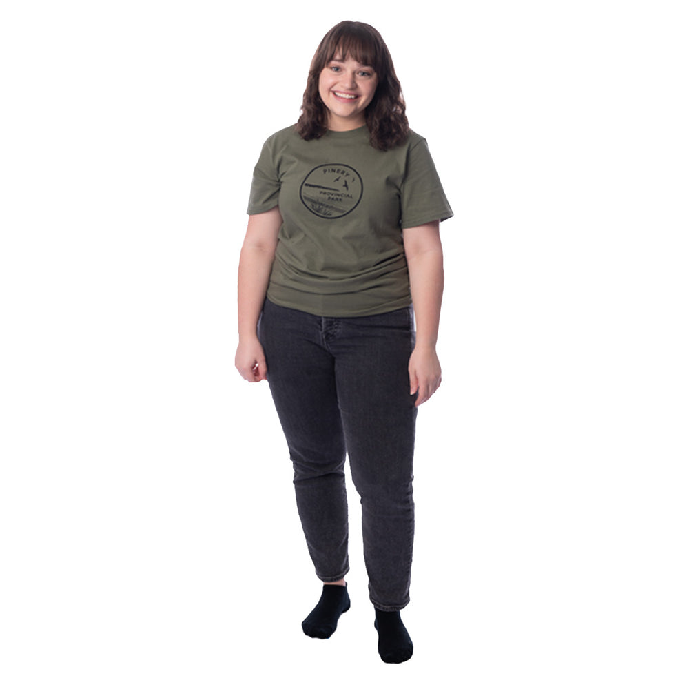 Female wearing Fatigue Green Unisex Park Specific T-shirt. Black Pinery park crest on centre chest.