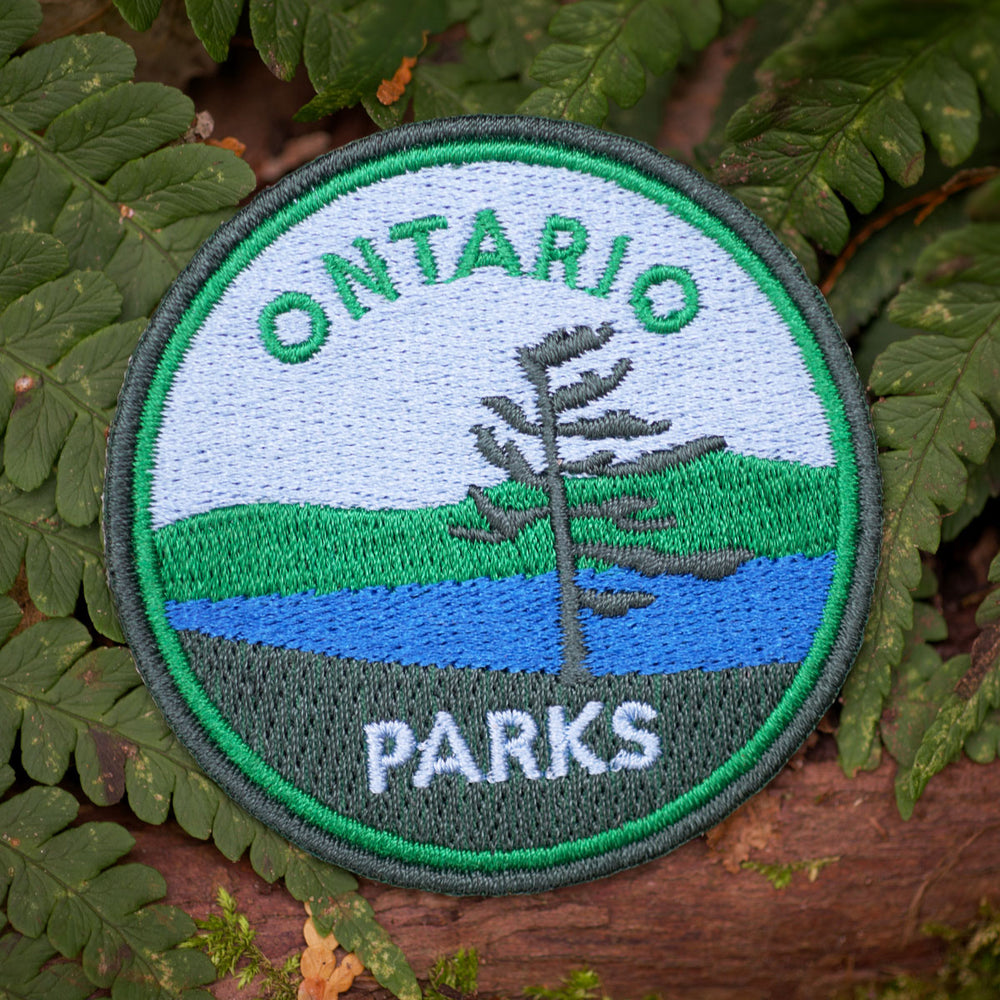 Round embroidered patch with green border and tree in foreground. Text reads Ontario Parks.